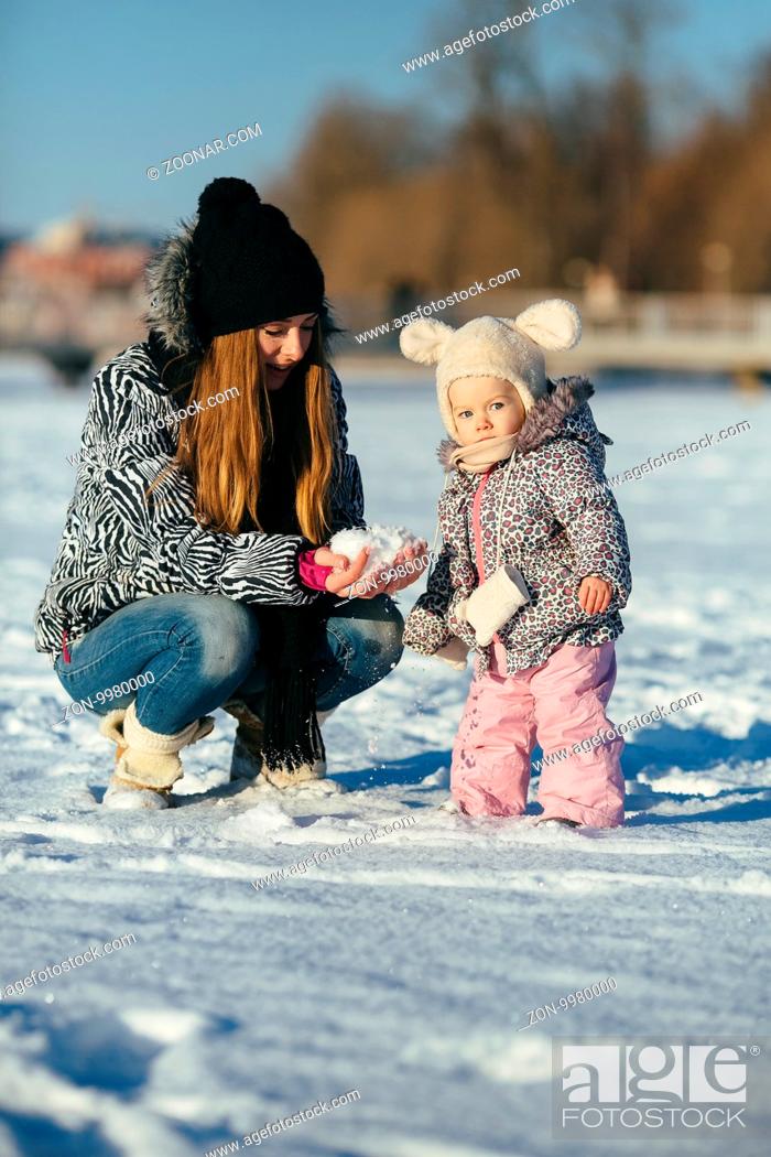 Photo de stock: happy family mother and baby girl daughter playing in winter outdoors in the snow.
