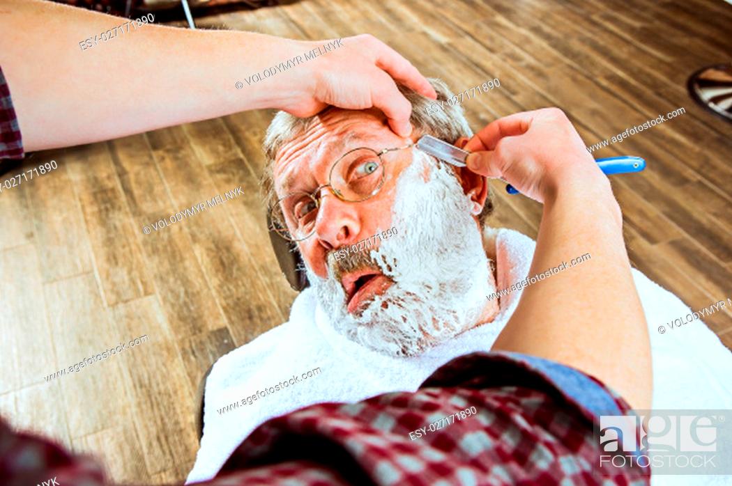 Photo de stock: The emotional senior man visiting hairstylist in barber shop.