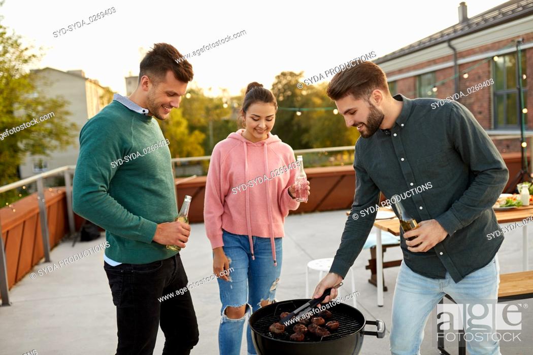 Stock Photo: happy friends having bbq party on rooftop.