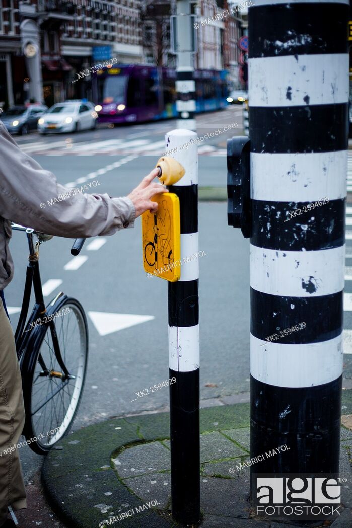 Stock Photo: Old Biker Pushing button for traffic light in Amsterdam, The Nederlands.