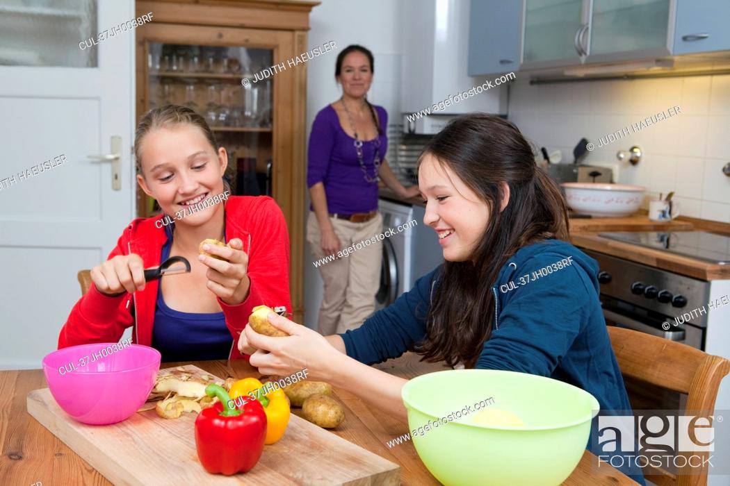 Stock Photo: Girls peeling vegetables in kitchen.