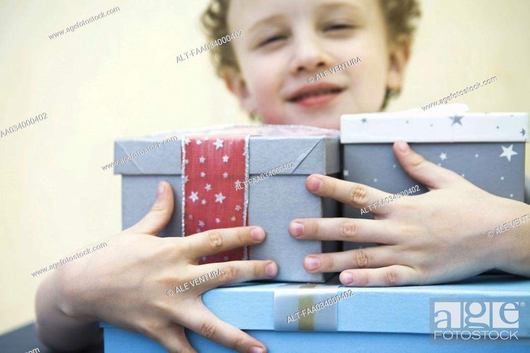 Stock Photo: Young boy holding armful of gifts, smiling.