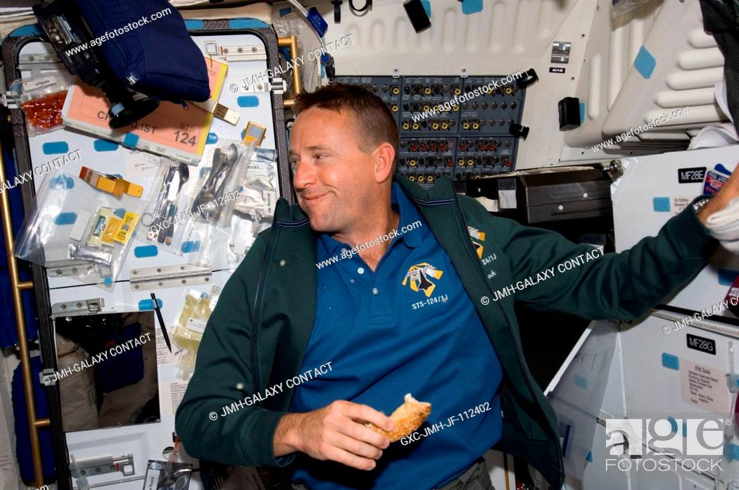 Stock Photo: Astronaut Ken Ham, STS-124 pilot, eats a snack at the galley on the middeck of Space Shuttle Discovery during flight day three activities.
