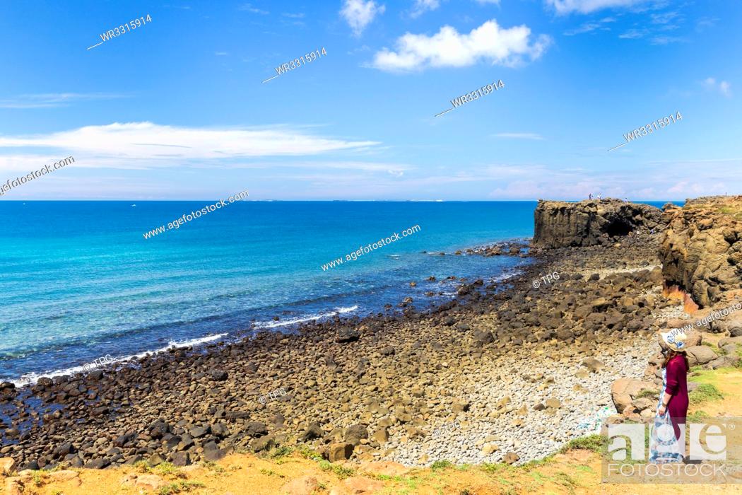 Photo de stock: Girl in red.Blue ocean and sky with white cloud beside the coast;hale Cave;Xiaomenyu;Penghu;Taiwan.