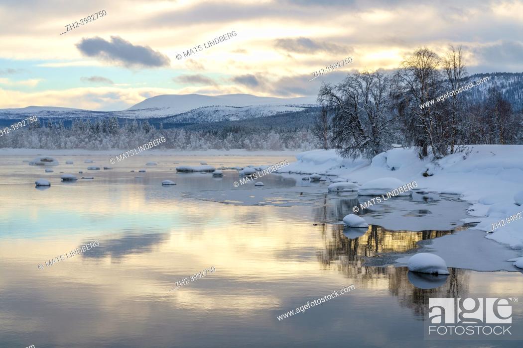 Stock Photo: Winter landscape with river, sky reflecting in the water, nice warm colors, mountain in background, Tjåmmotis, Swedish Lapland, Sweden.