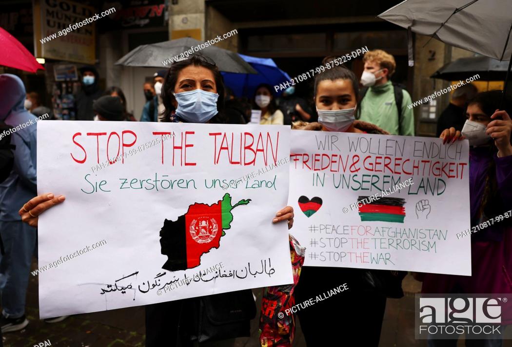 Stock Photo: 17 August 2021, North Rhine-Westphalia, Cologne: Women from Afghanistan hold banners reading ""Stop the Taliban - They are destroying our country"" and ""We.