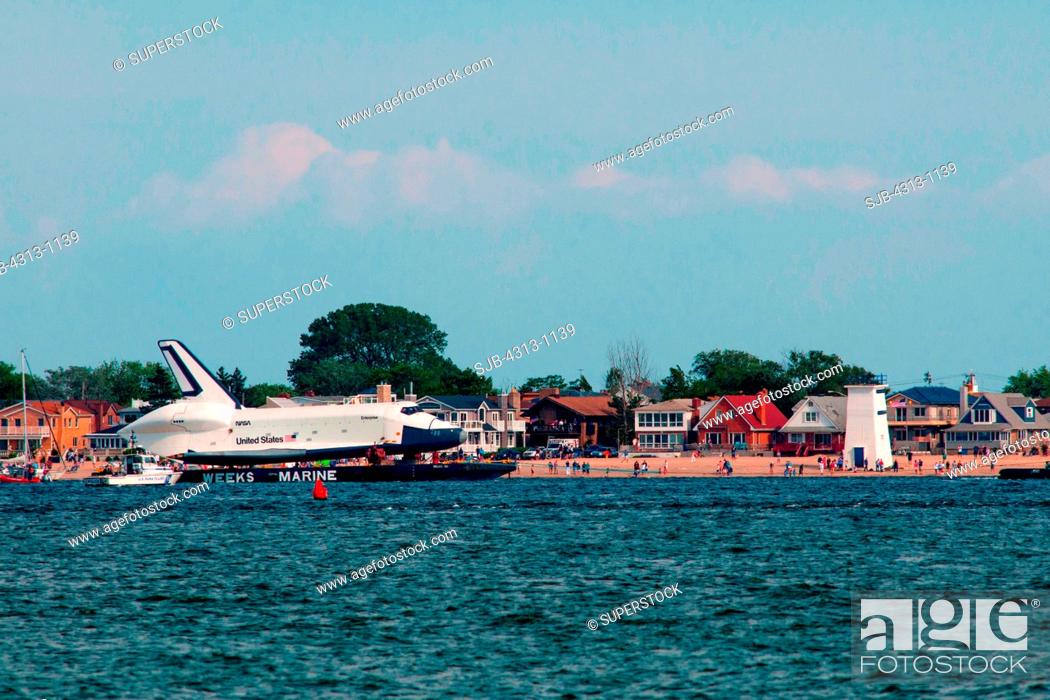 Stock Photo: The Space Shuttle prototype Enterprise sails by barge past Rockaway and Breezy Point, Queens, as it travels from JFK airport to the Intrepid Sea.