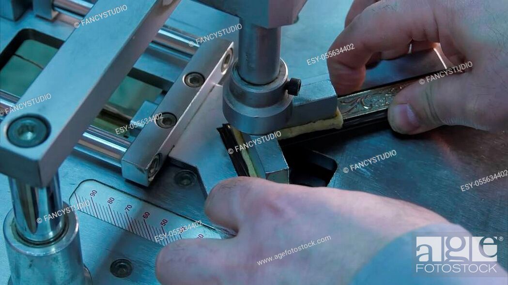 Stock Photo: Craftsman working on frame, glue together pieces in special machine. Close up. Professional shot in 4K resolution. 083. You can use it e. g.
