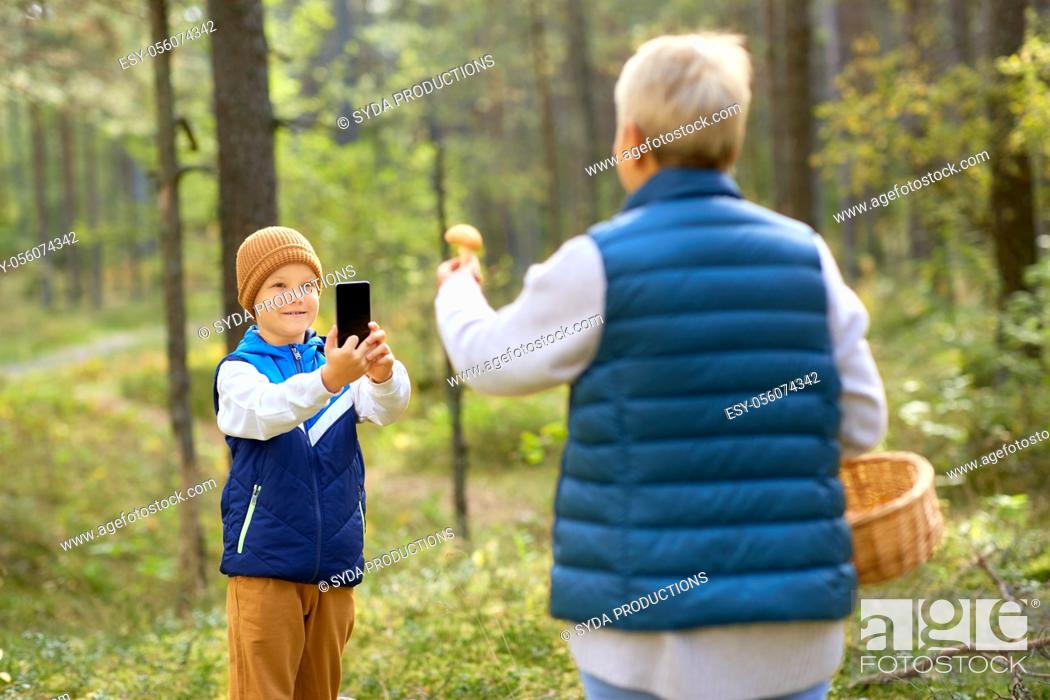 Stock Photo: grandson photographing grandmother with mushroom.