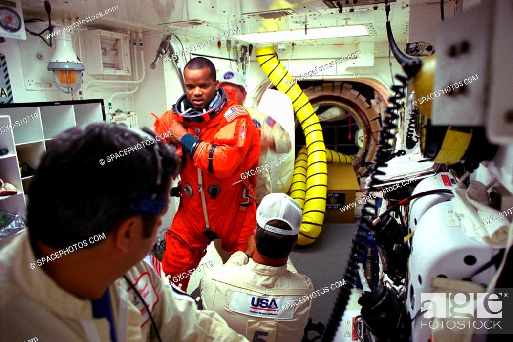 Stock Photo: 08/07/1997 --- STS-85 Mission Specialist Robert L. Curbeam, Jr. is assisted with his ascent/reentry flight suit by white room closeout crew members Mike.