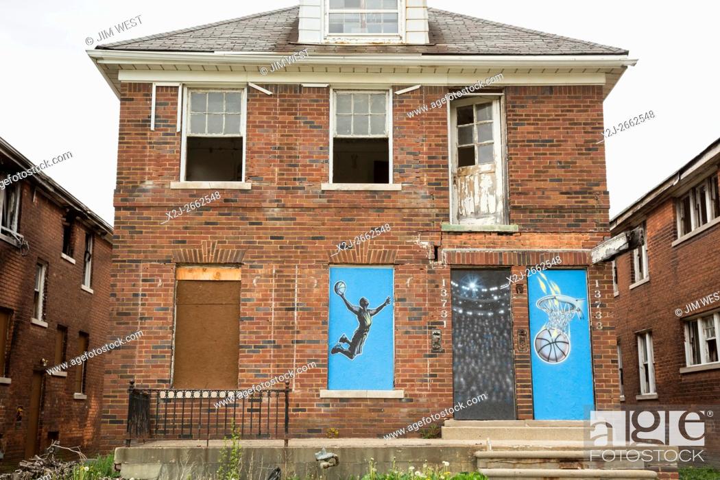 Stock Photo: Detroit, Michigan - A vacant and vandalized home in Detroit's Osborn neighborhood. The boarded-up windows and doors are decorated with sports themes.