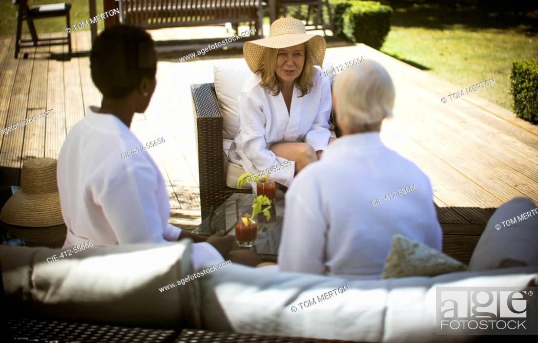 Imagen: Senior women friends talking on summer patio.