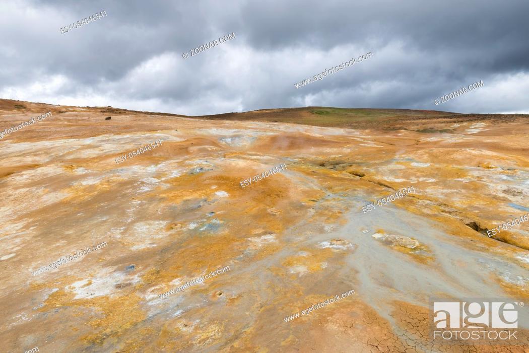 Stock Photo: Geothermal landscape Krafla on Iceland with red dirt, steam and a hot water stream down a hill.