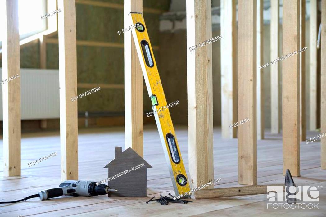 Stock Photo: Close-up of small brown model house and building tools on wooden planks in unfinished room under construction background.