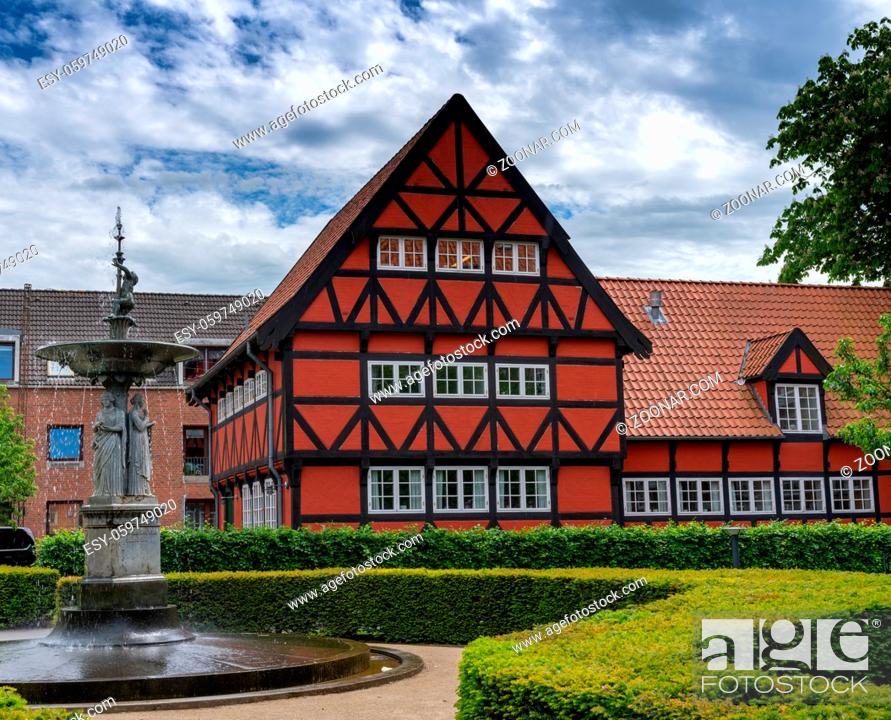 Stock Photo: Aalborg, Denmark - 7 June, 2021: historic red half-timbered house and the Kayerod fountain in the old town city center of Aalborg.