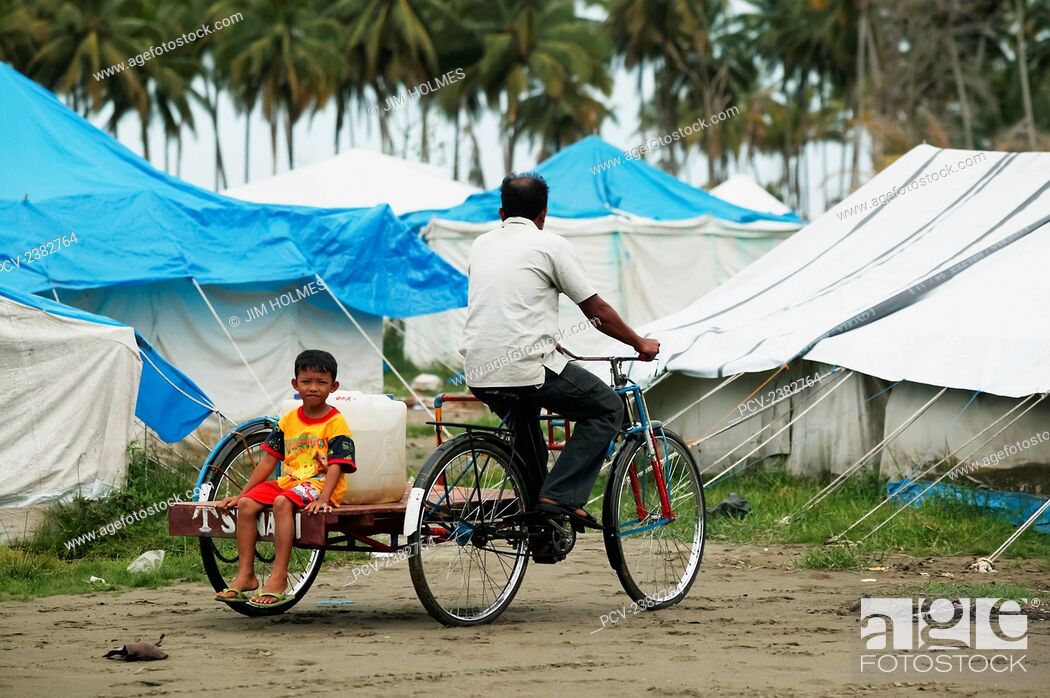 Stock Photo: A man and his son cycle back to their home, near Meulaboh, with a large container of water that came from emergency standpipes after the Indian Ocean tsunami in.