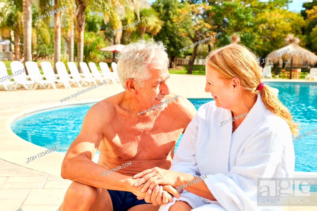 Stock Photo: Glückliches verliebtes Senioren Paar sitzt am Pool im Wellness Urlaub.