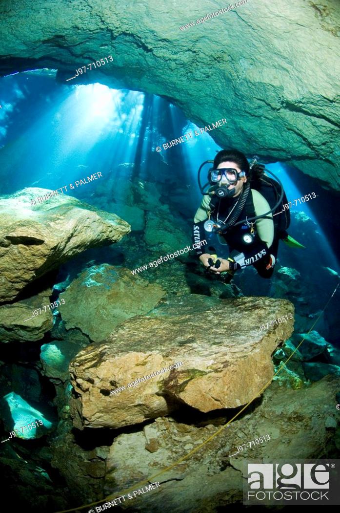 Stock Photo: Mario, a cavern/cave guide with Dive Adventuras, dives near the stricking sunlight rays visible during a dive in Chac Mool (God of Rain) Cenote, Riviera Maya.