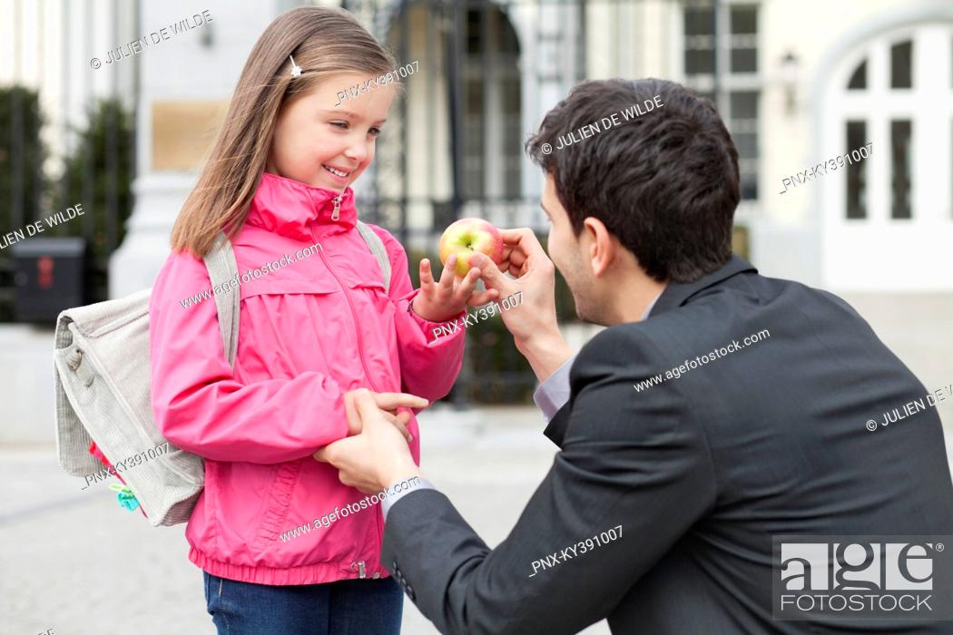 Stock Photo: Man giving an apple to his daughter.
