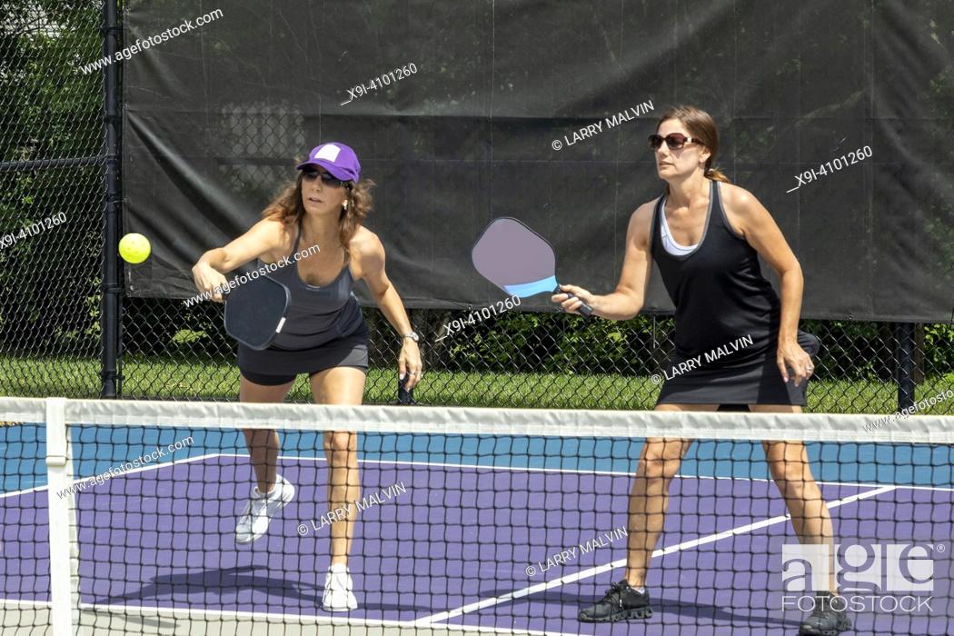 Stock Photo: Two pickleball players in action at the net on a suburban pickleball court during summer.