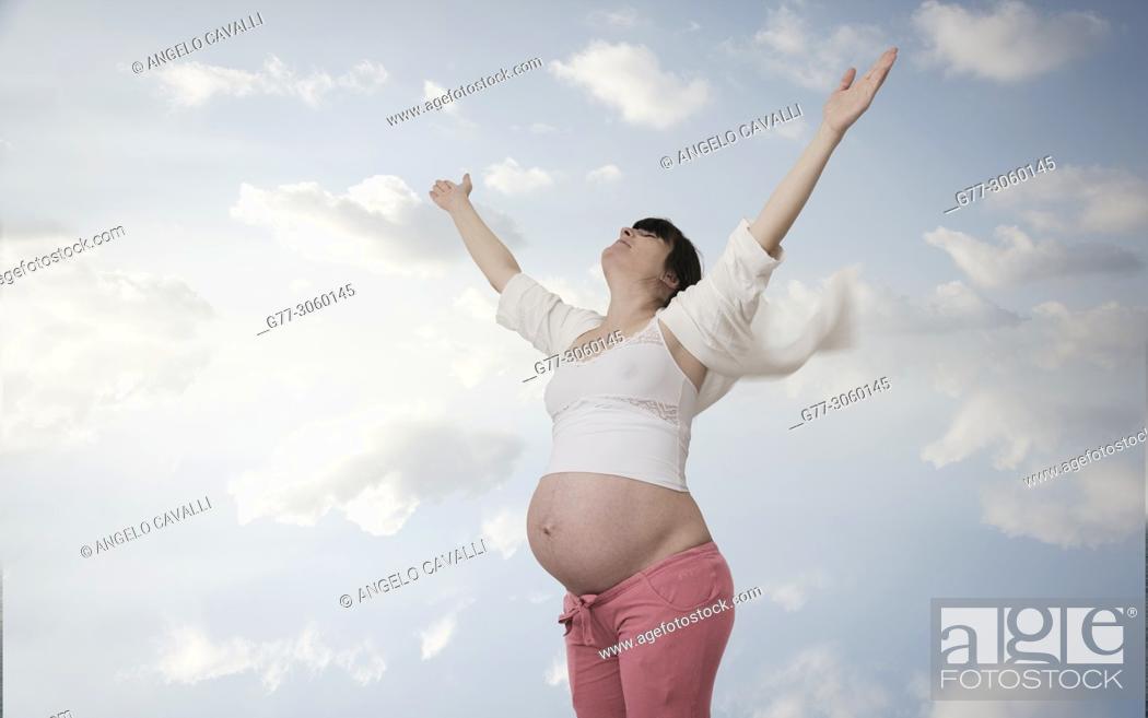 Stock Photo: Pregnant woman lifting arms to sky.