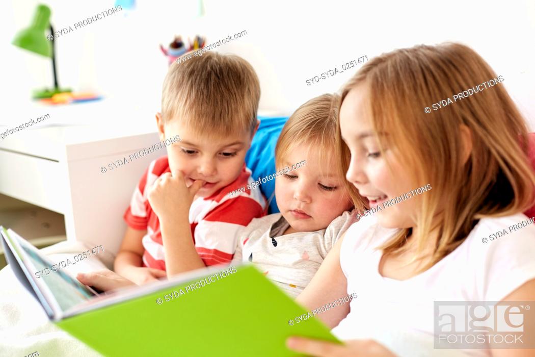 Stock Photo: little kids reading book in bed at home.