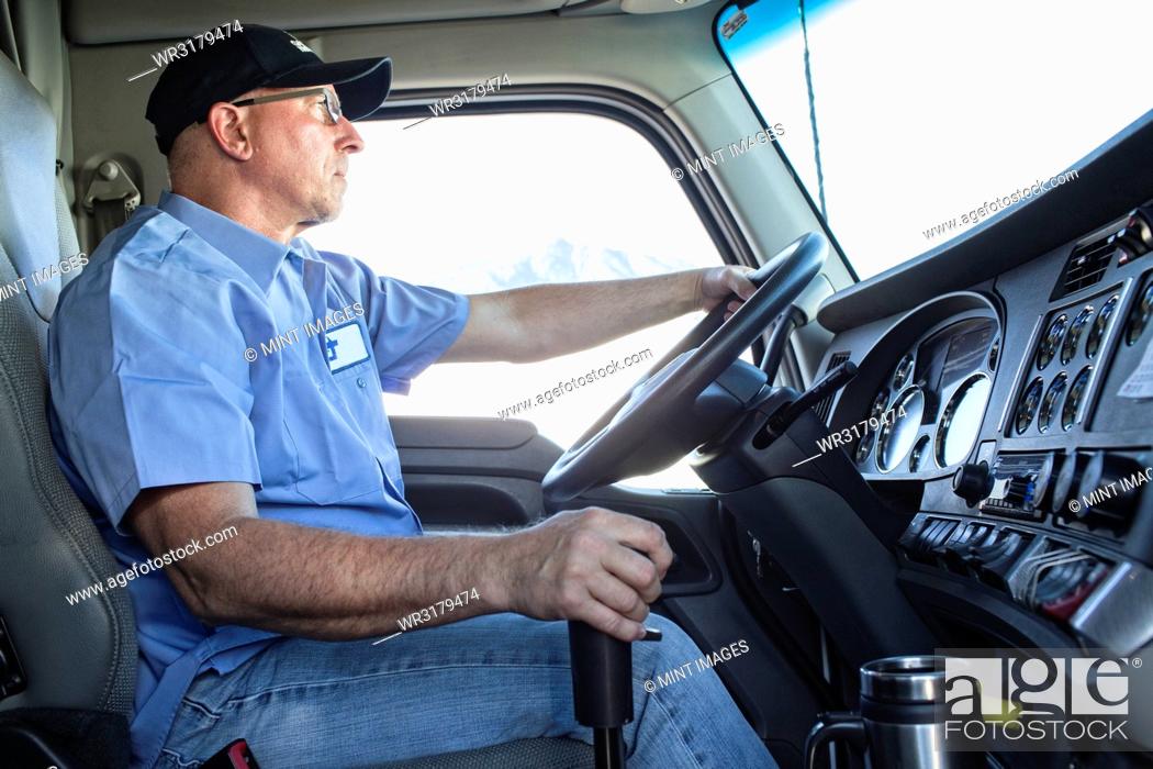Stock Photo: Caucasian man truck driver in the cab of his commercial truck.