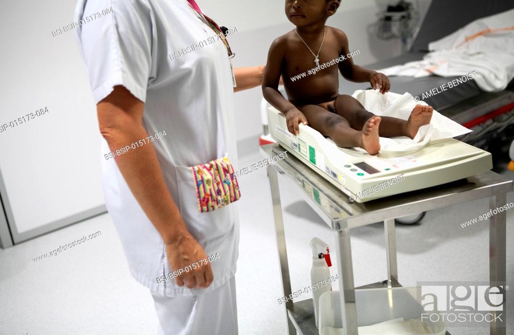 Stock Photo: Reportage in the pediatric emergency unit in a hospital in Haute-Savoie, France. An auxiliary nurse weighs a baby.