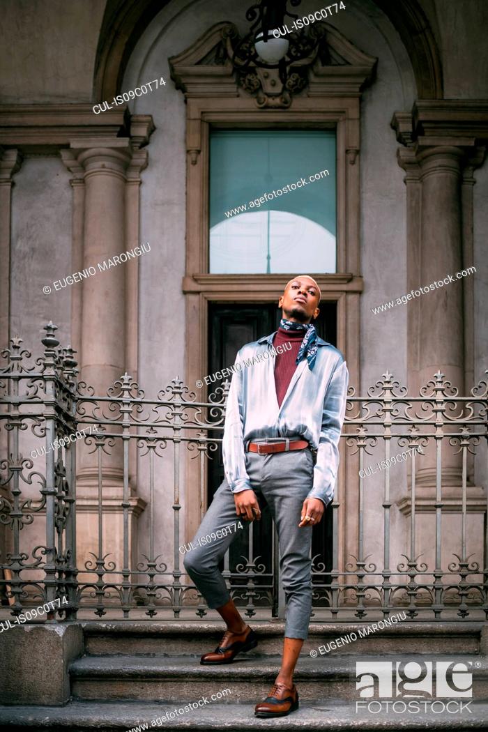 Stock Photo: Stylish man standing on steps of period building, Milan, Italy.