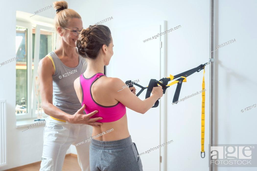 Stock Photo: Woman using sling trainer during physical therapy to recover from an injury.