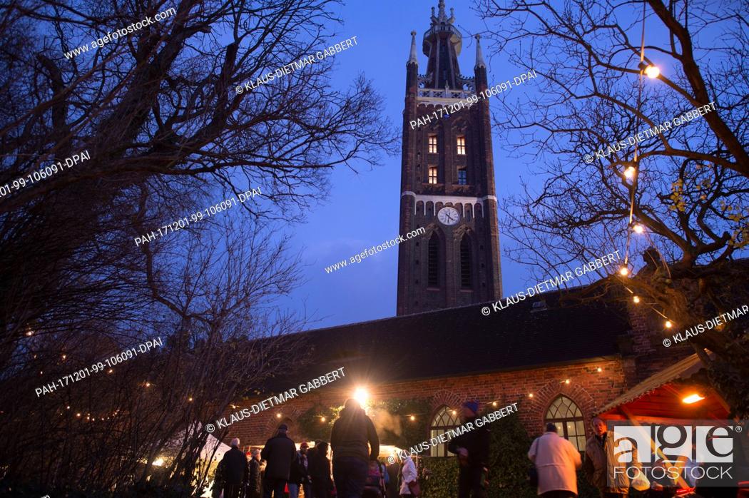 Stock Photo: Visitors walk across the Advent market in Oranienbaum-Woerlitz, Â Germany, 01 December 2017. The tower of the St. Petri Church can be seen in the background.