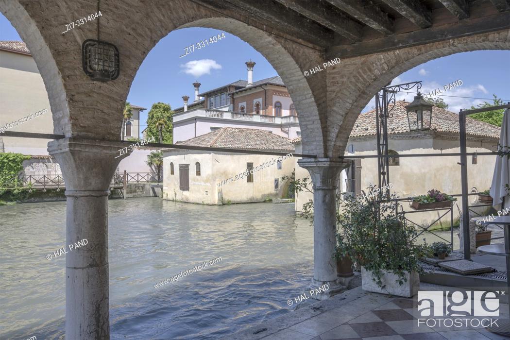 Stock Photo: picturesque cityscape through the arches of Renaissance loggia near Lemene river, shot at Mediterranean little town of Portogruaro, Venezia, Veneto, Italy.