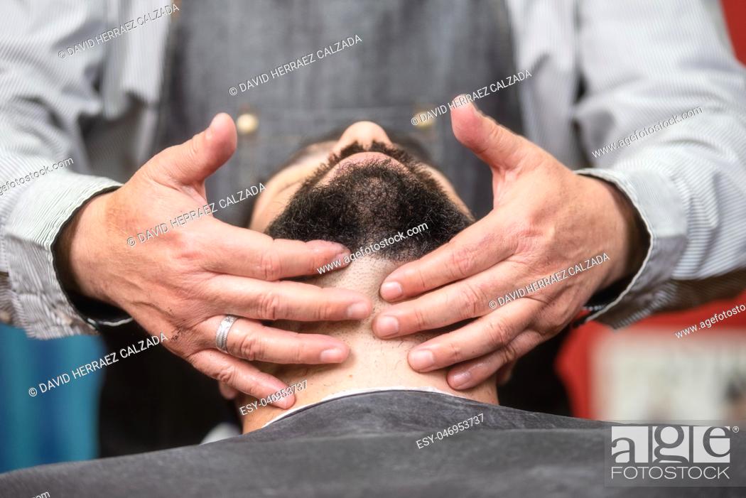 Imagen: Hair stylist applying after shaving lotion at barber shop .
