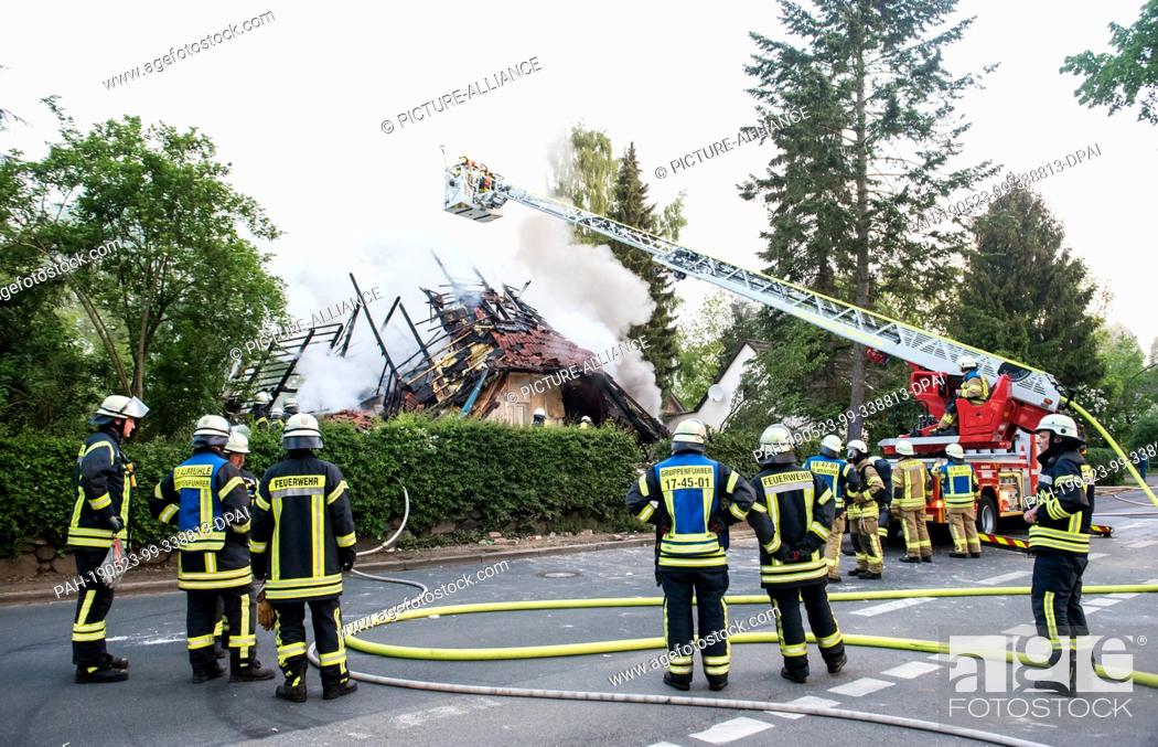 Stock Photo: 23 May 2019, Schleswig-Holstein, Wohltorf: Firefighters are standing in front of the ruins of a house that was destroyed in a fire.