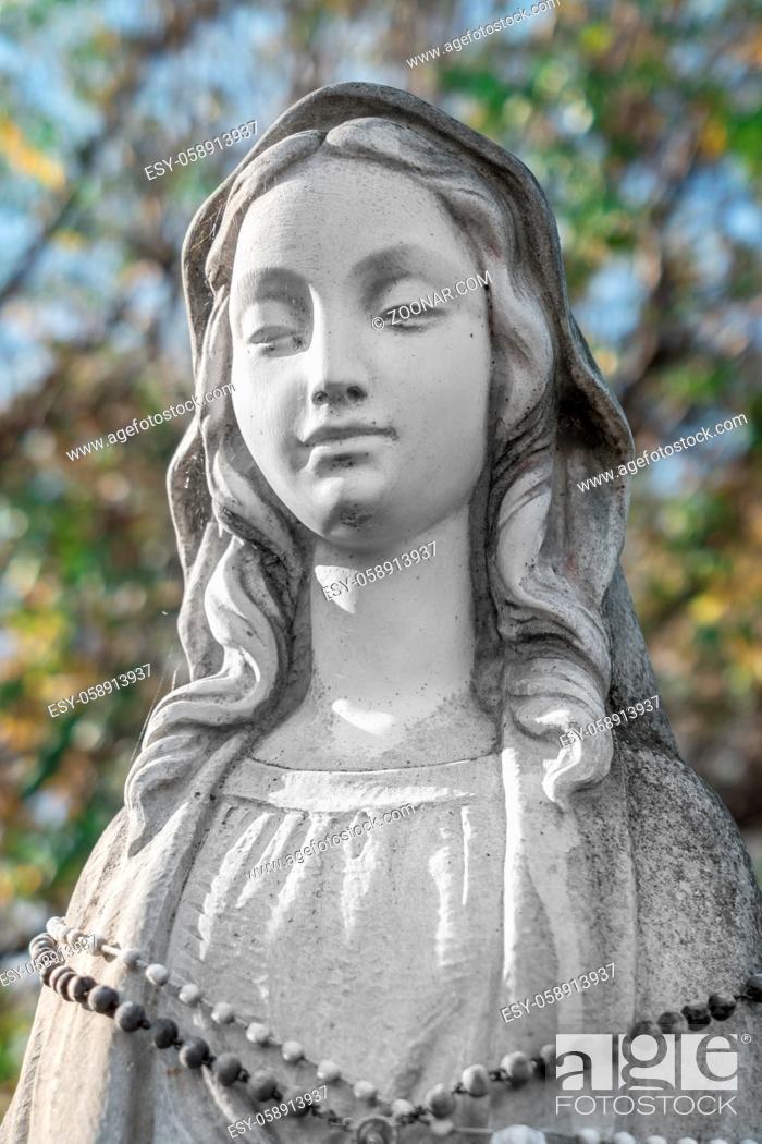 Stock Photo: Virgin Mary Statue. On defocused blurry background some green trees. Ideal for concepts and festivity.