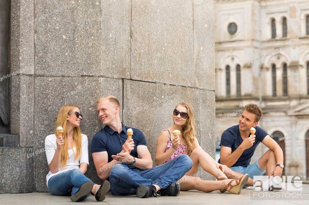 Stock Photo: Two couples sitting on the groung and eating ice creams in the city.