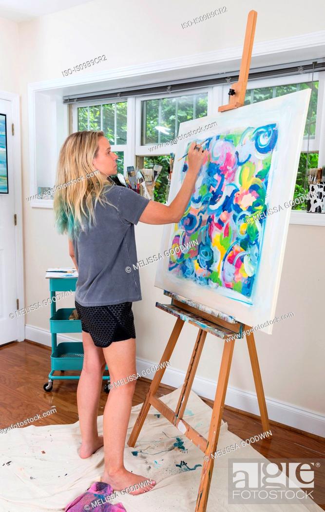Stock Photo: Female artist painting abstract canvas in studio.