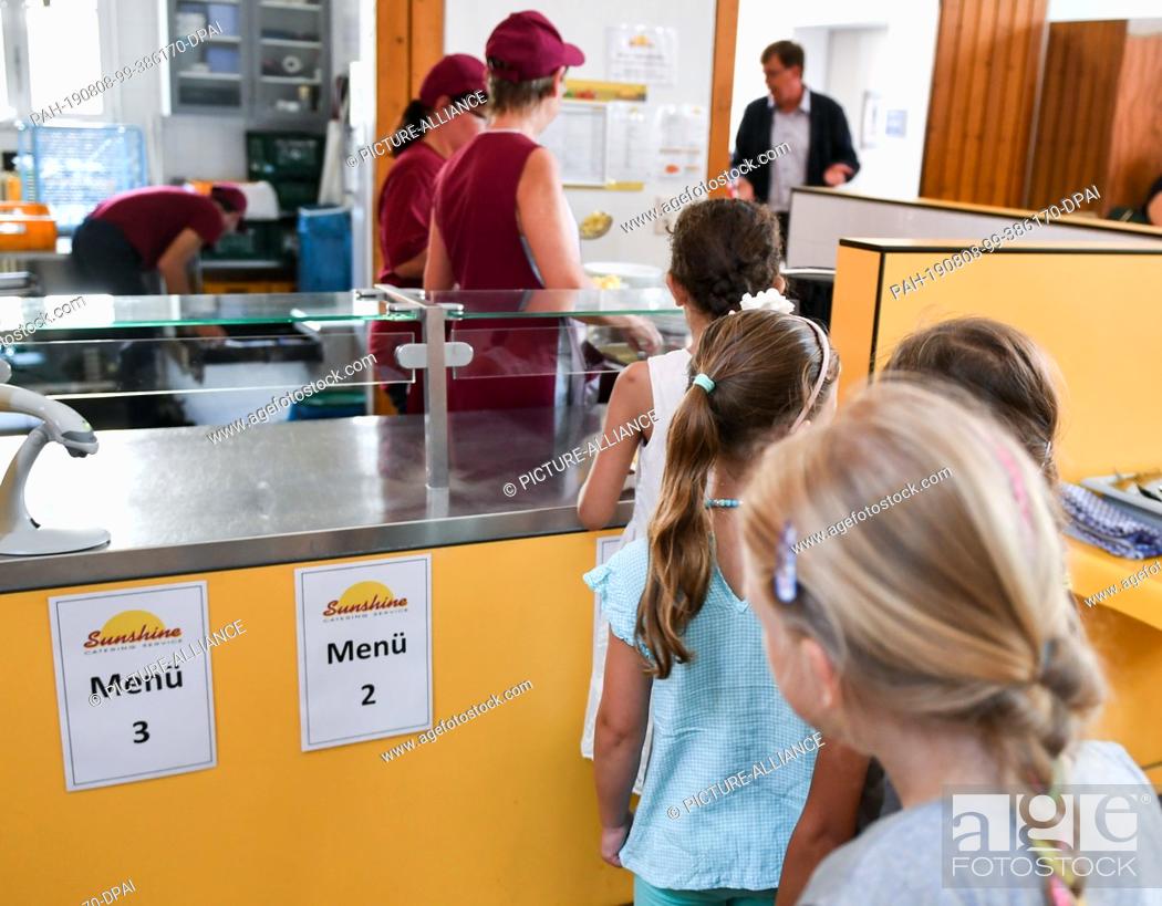 Stock Photo: 07 August 2019, Berlin: Before lunch, pupils stand in the cafeteria in the primary school on the Wuhlheide in the queue in front of the food counter.