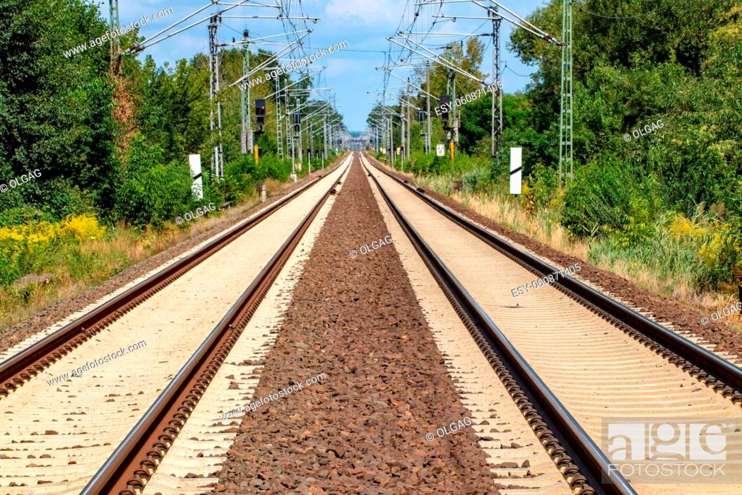 Stock Photo: Transit Railroad tracks going through a scenic forested countryside with a blue sky and fluffy clouds above.
