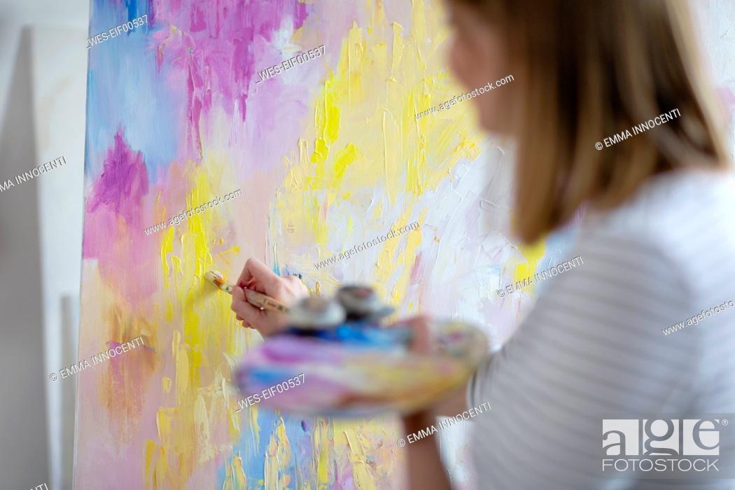 Stock Photo: Mid adult woman painting abstract canvas at home studio.