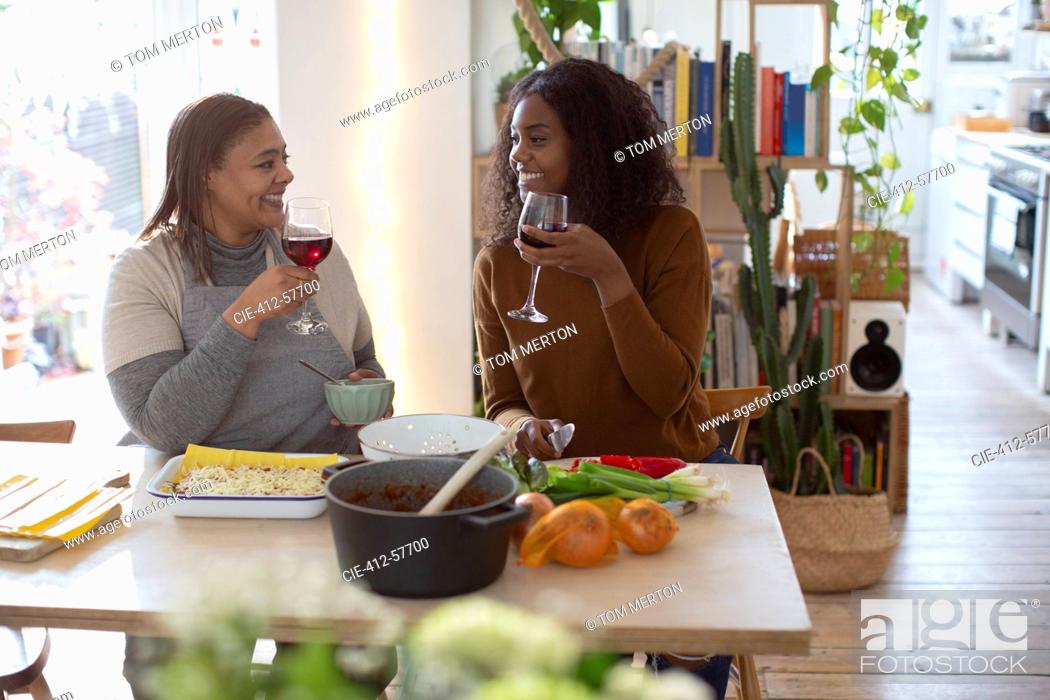 Stock Photo: Mother and daughter cooking and drinking red wine at table.
