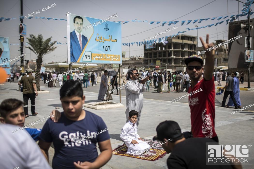 Stock Photo: dpatop - An Iraqi man and his son attend Friday prayers backdropped by campaign posters for the upcoming parliamentary elections in the Sadr City suburb of.