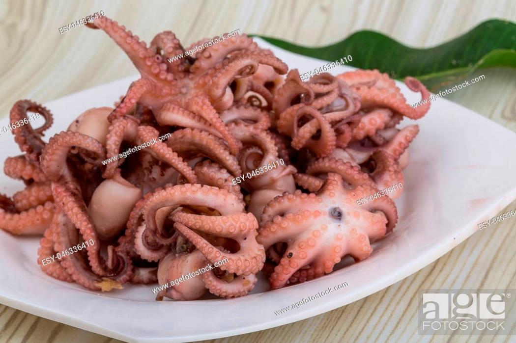 Stock Photo: Boiled octopus in the bowl on wooden background.
