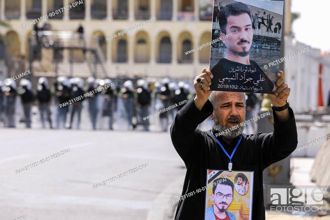 Stock Photo: 01 October 2021, Iraq, Baghdad: An Iraqi man holds pictures of one of those who killed in October 2019 anti-government protests.