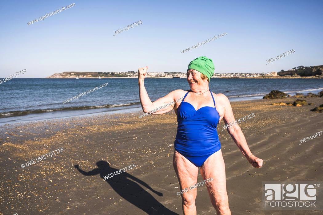 Photo de stock: Woman showing biceps at beach on sunny day.