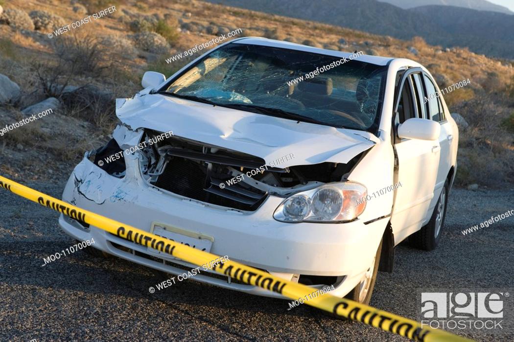 Stock Photo: Smashed car cordoned off behind police tape.