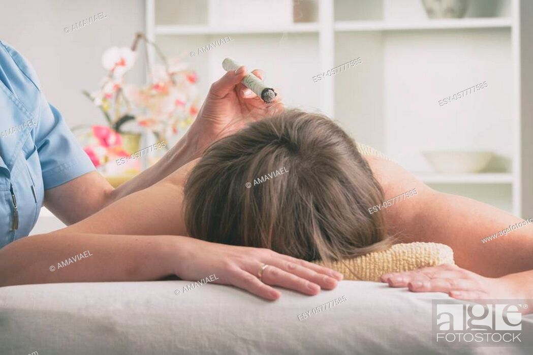 Imagen: Alternative medicine therapist doing moxa treatment on her client.