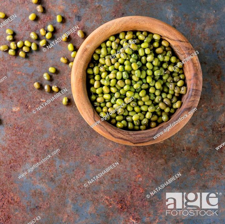 Stock Photo: Healthy superfood. Uncooked green mungo beans in olive wood bowl over old rusty iron background. Top view. With copy space? Square image.