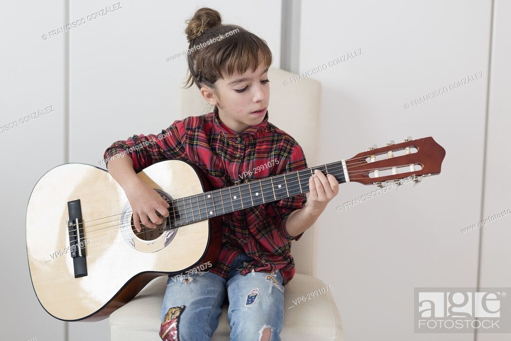 Stock Photo: 10 year old girl playing the Spanish guitar. Horizontal shot.