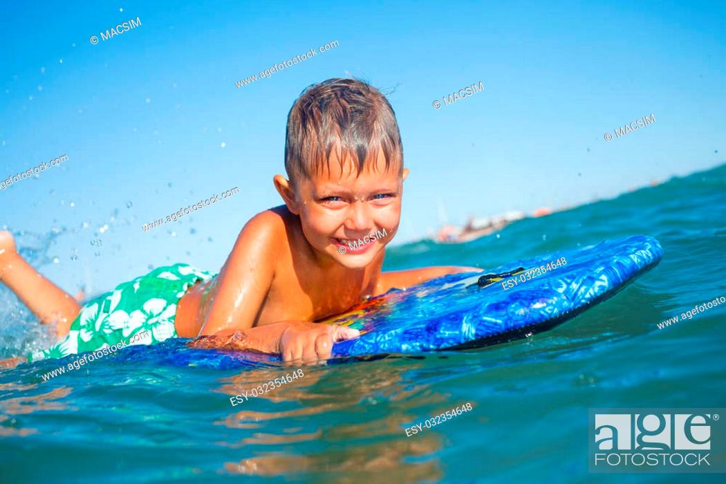 Stock Photo: Boy has fun on the surfboard in transparency sea.